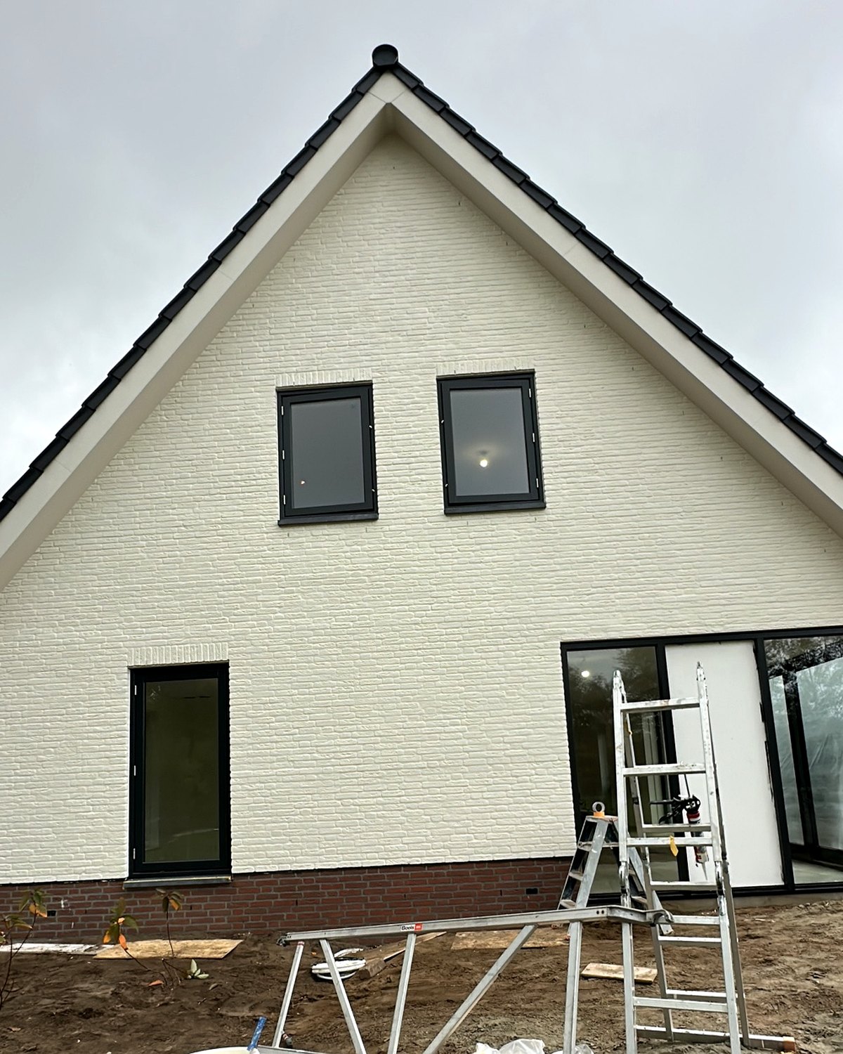 Schilder werkt vanuit een hoogwerker aan een woning
